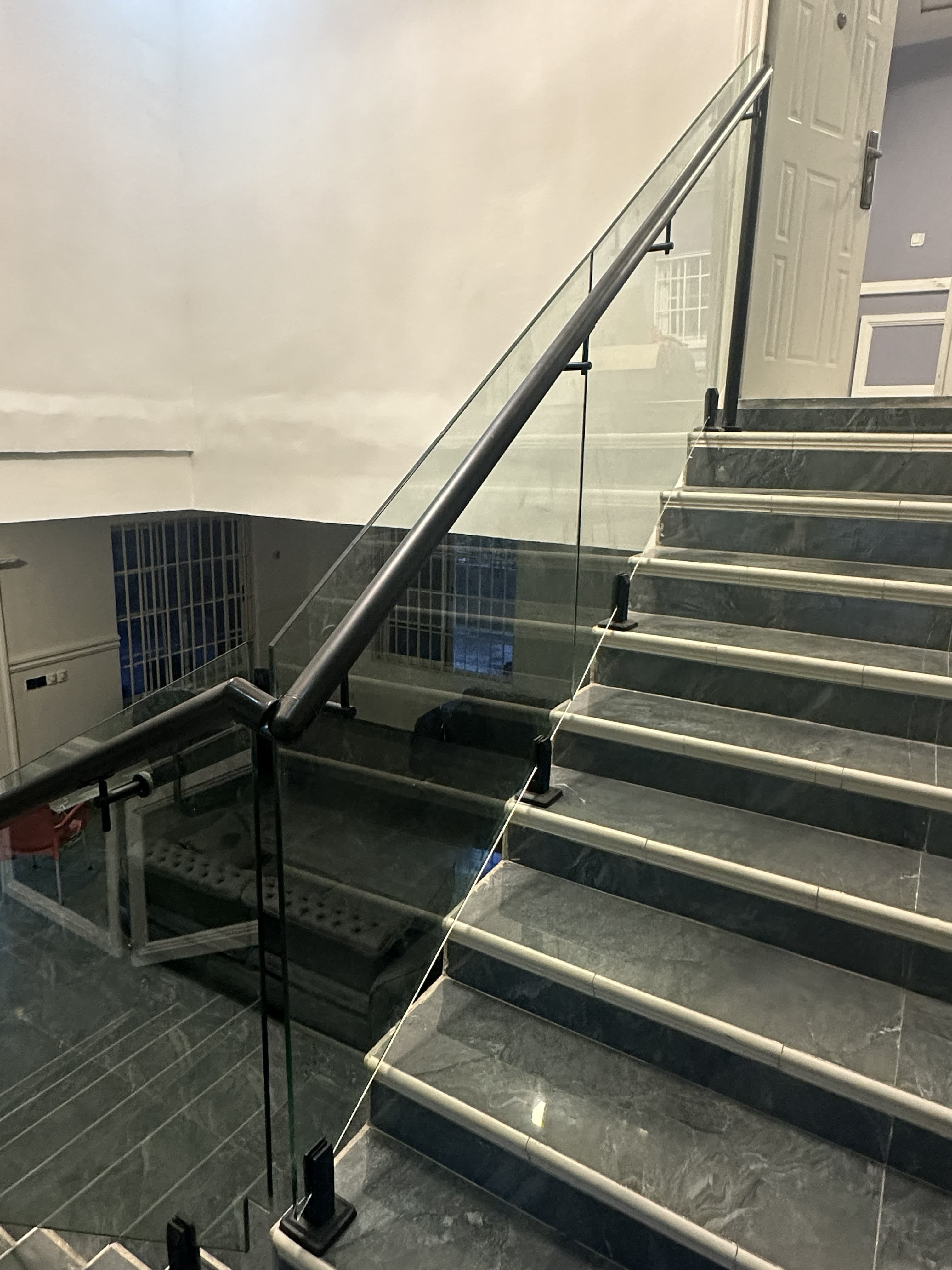 Staircase glass railing with black spigots and continuous handrail