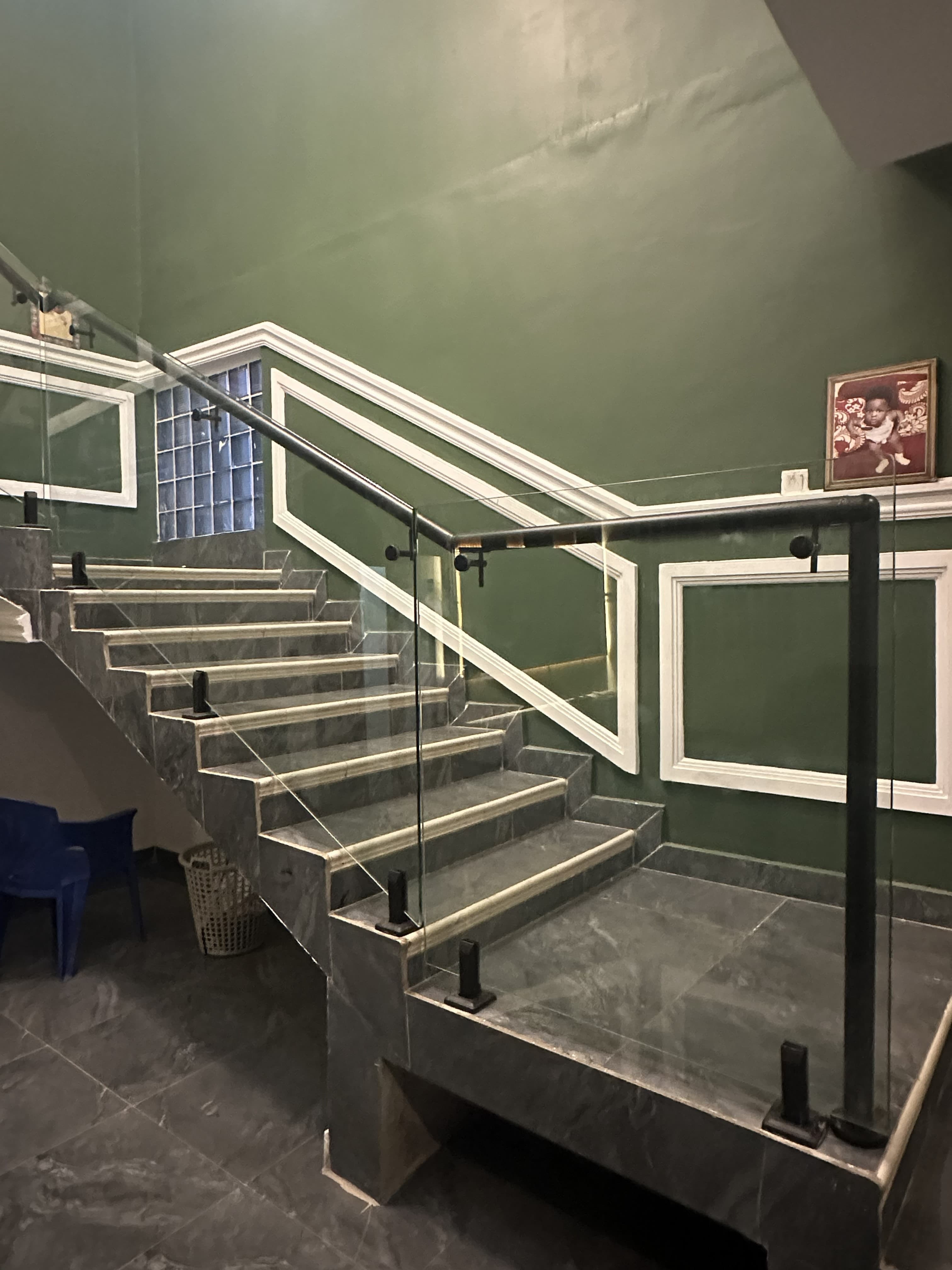 Modern staircase glass railing with black posts and handrail