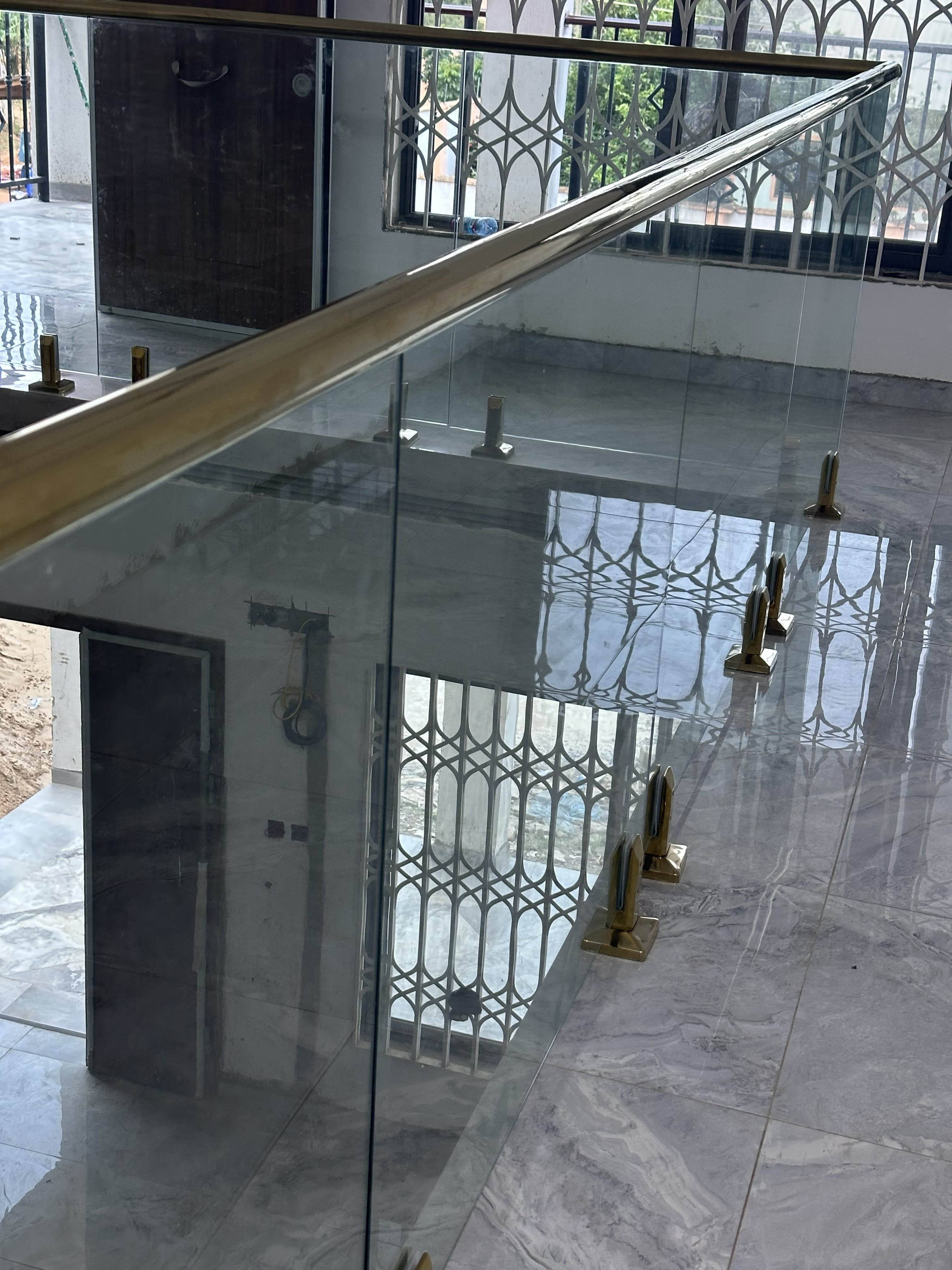 Indoor glass railing with gold spigots and top handrail
